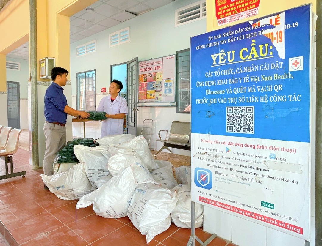 Cán bộ chương trình đang cấp màn và võng bọc màn tẩm hóa chất tại Trạm Y tế xã Long Tân.